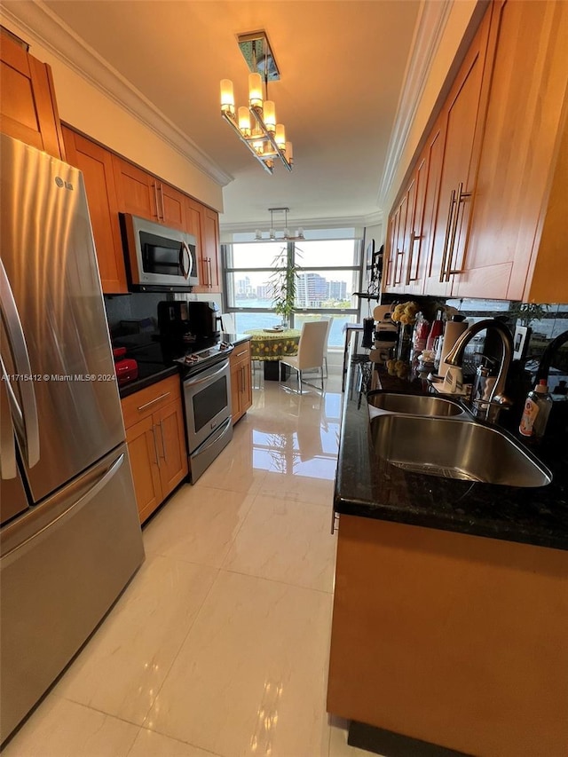 kitchen featuring dark stone counters, stainless steel appliances, crown molding, sink, and decorative light fixtures