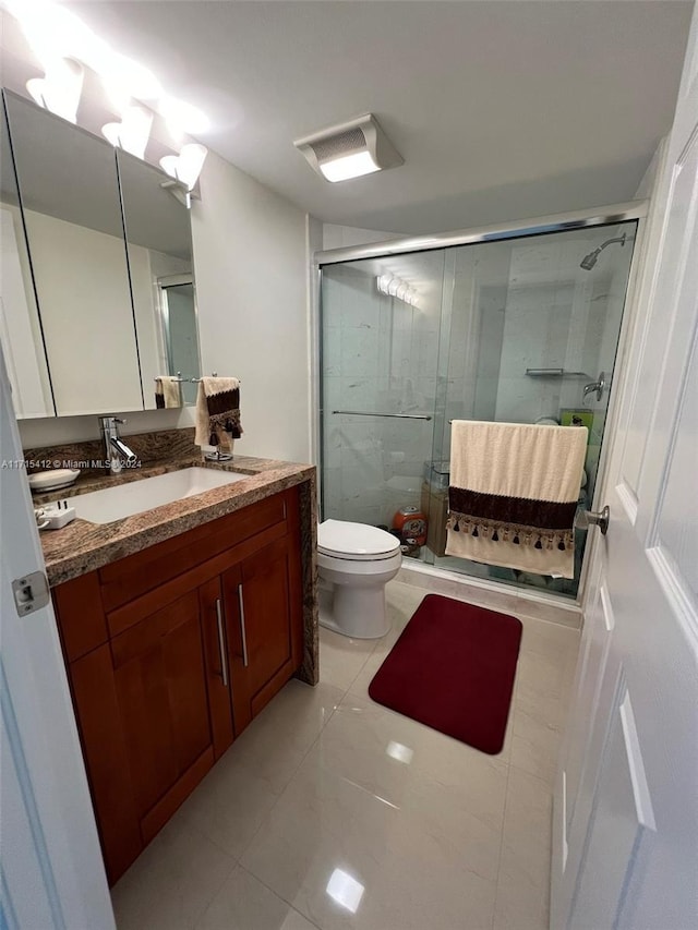 bathroom featuring tile patterned flooring, vanity, toilet, and an enclosed shower