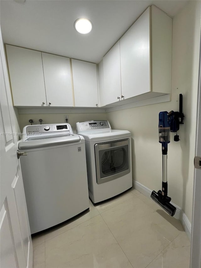 laundry room featuring cabinets, washer and dryer, and light tile patterned flooring