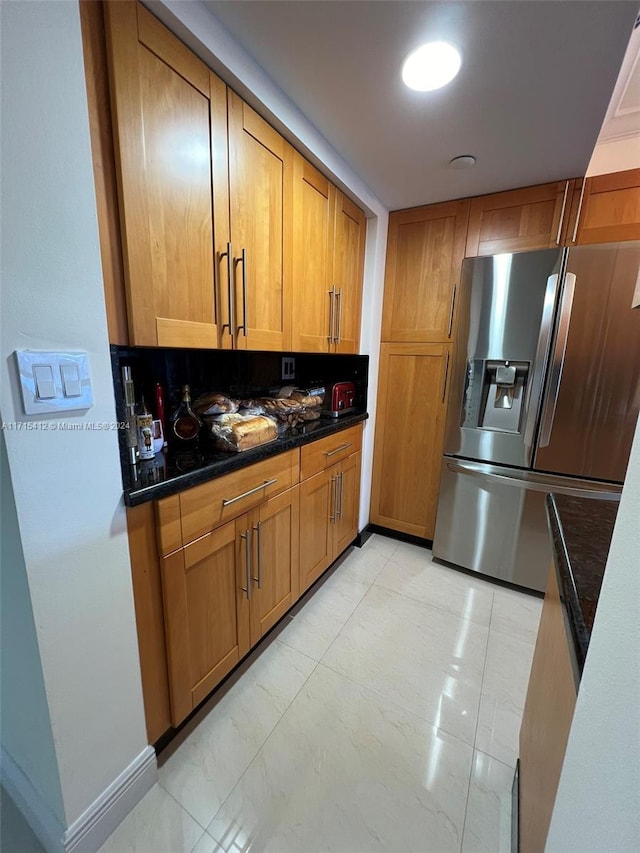 kitchen with stainless steel refrigerator with ice dispenser and dark stone counters