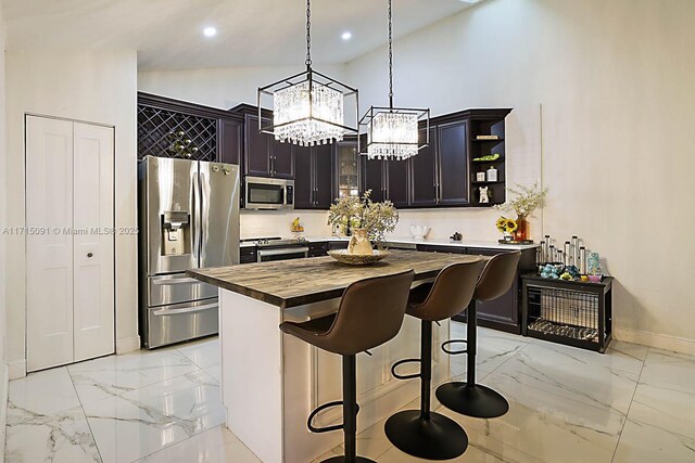 kitchen with a breakfast bar, stainless steel appliances, decorative light fixtures, a center island, and butcher block countertops