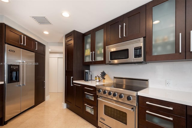 kitchen featuring high quality appliances, dark brown cabinets, and light tile patterned floors