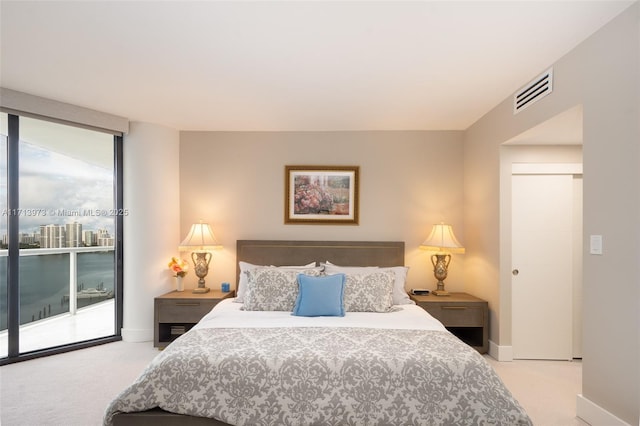 bedroom featuring expansive windows, light colored carpet, and access to outside