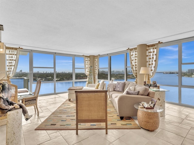 living room with floor to ceiling windows, a water view, and a textured ceiling