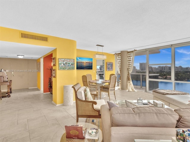 tiled living room featuring a textured ceiling, a water view, and floor to ceiling windows