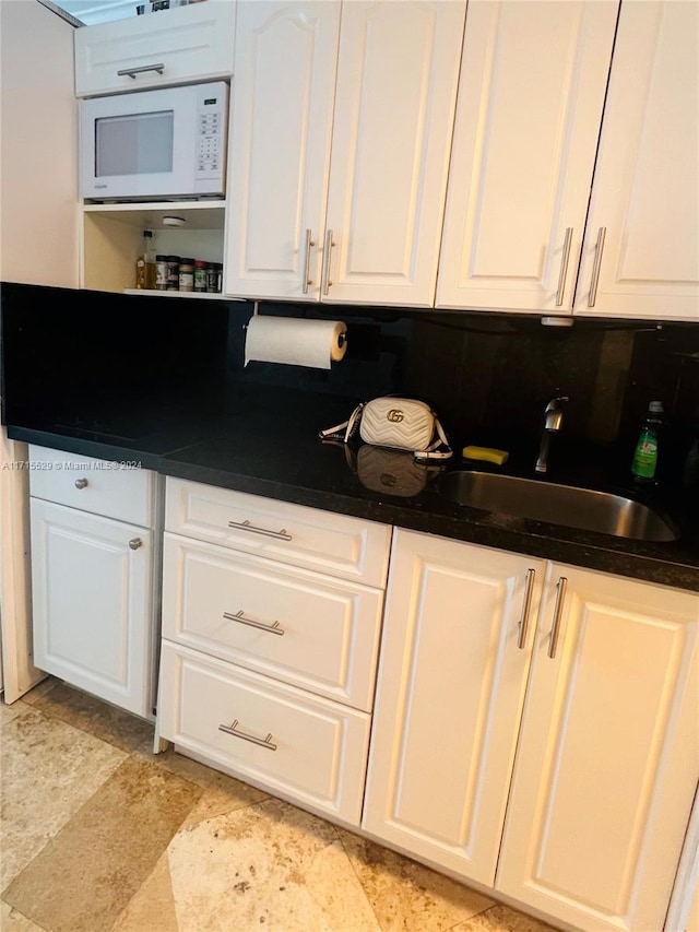 kitchen featuring decorative backsplash, white cabinetry, and sink