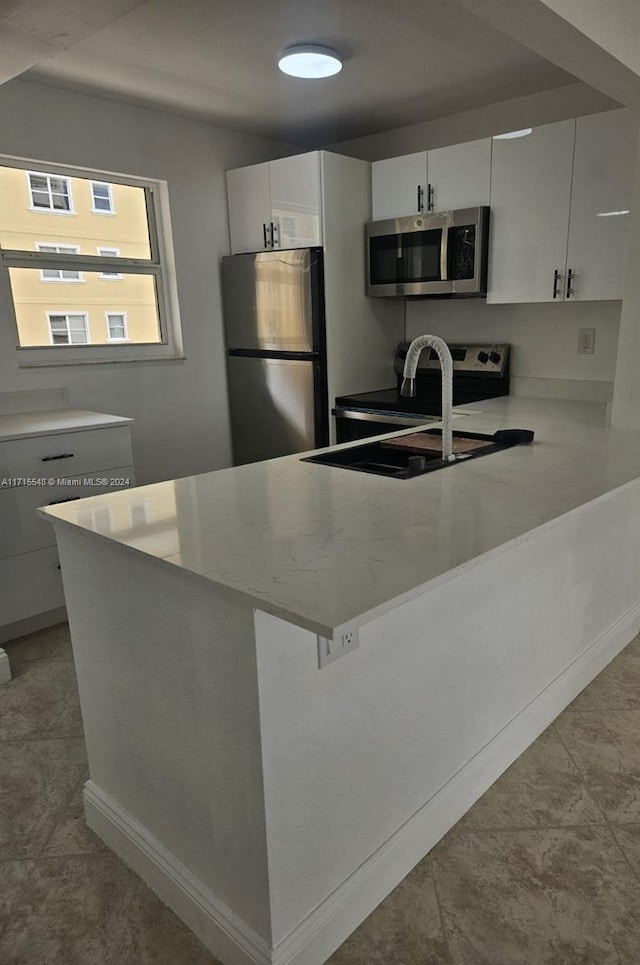 kitchen featuring light stone countertops, sink, stainless steel appliances, light tile patterned floors, and white cabinets