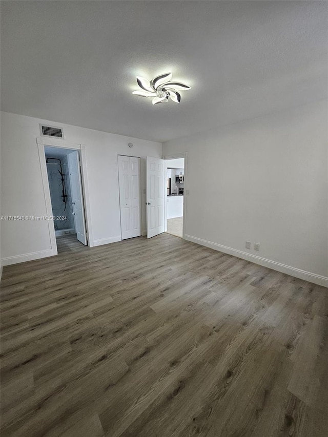 unfurnished bedroom featuring ensuite bathroom and dark hardwood / wood-style floors