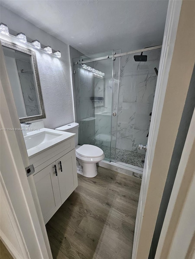 bathroom featuring vanity, hardwood / wood-style flooring, toilet, and a shower with shower door