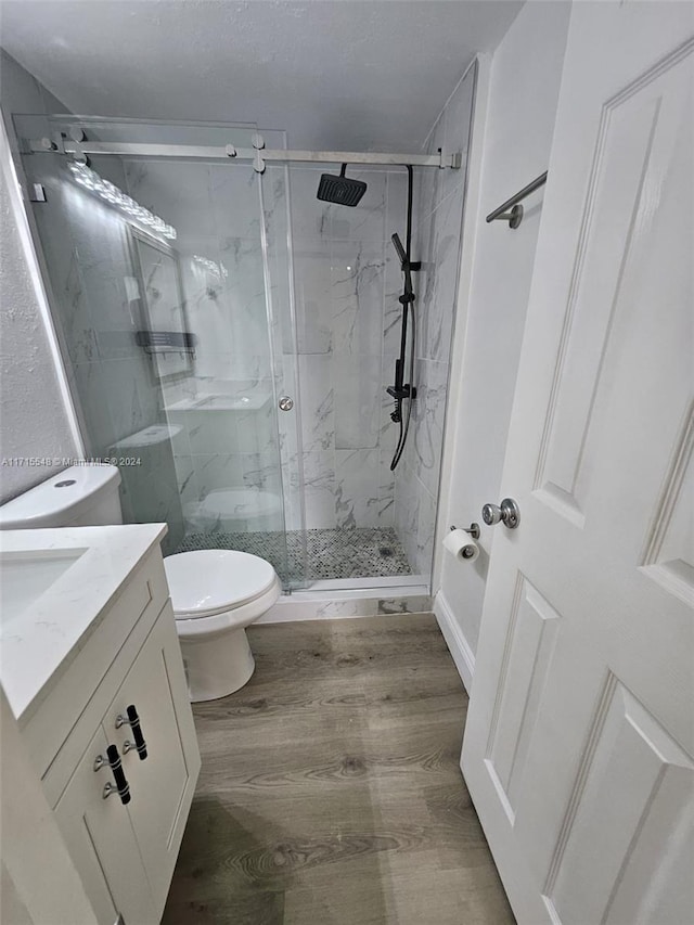 bathroom featuring vanity, hardwood / wood-style flooring, toilet, and walk in shower