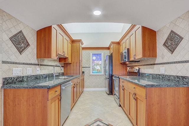 kitchen featuring sink, dark stone countertops, light tile patterned floors, tile walls, and appliances with stainless steel finishes