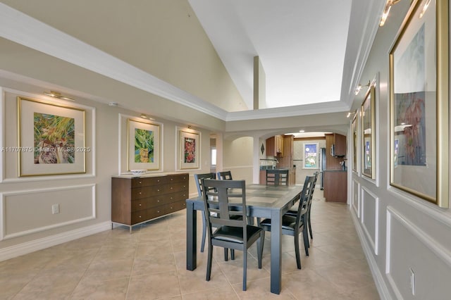 dining space with light tile patterned floors, ornamental molding, and high vaulted ceiling