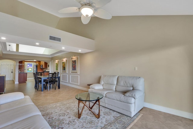 living room with ceiling fan, light tile patterned flooring, and vaulted ceiling