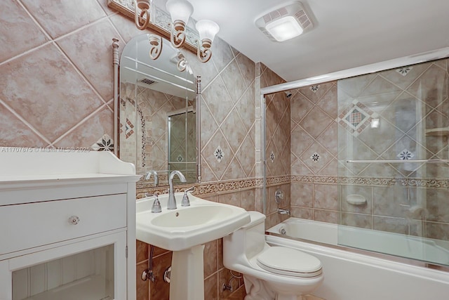 bathroom featuring shower / bath combination with glass door, tile walls, and toilet