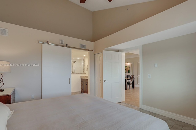 bedroom featuring ceiling fan, a towering ceiling, connected bathroom, light tile patterned flooring, and a closet