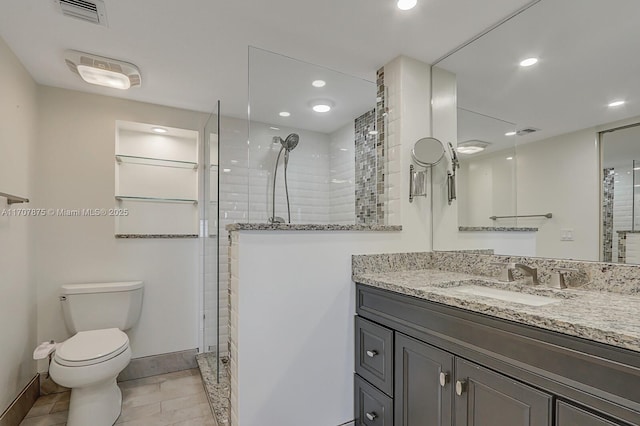 bathroom featuring tiled shower, tile patterned floors, vanity, and toilet