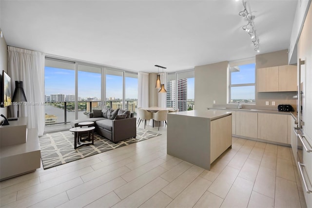 kitchen featuring light brown cabinets, decorative light fixtures, a kitchen island, and floor to ceiling windows