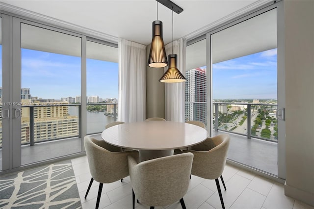 dining space with expansive windows, a water view, and a healthy amount of sunlight