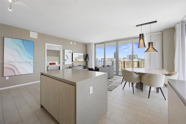 kitchen featuring light brown cabinetry, floor to ceiling windows, a center island, and pendant lighting