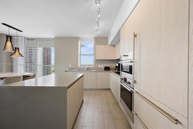 kitchen featuring stainless steel oven, pendant lighting, light brown cabinetry, a kitchen island, and light wood-type flooring