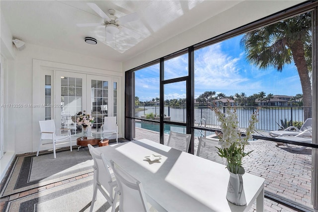 sunroom with ceiling fan, a water view, and french doors