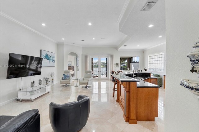 kitchen with sink, french doors, crown molding, and a spacious island