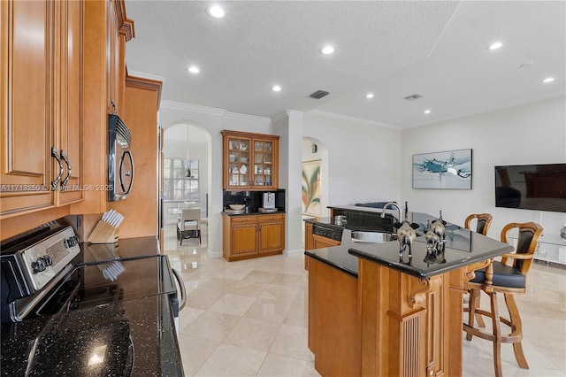 kitchen featuring a center island with sink, range, crown molding, a breakfast bar, and sink