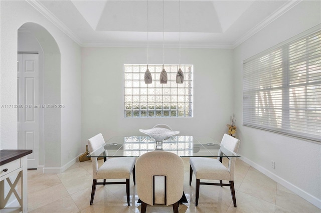 dining area with ornamental molding, light tile patterned floors, and a tray ceiling