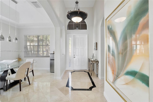 tiled entryway with a high ceiling and ornamental molding