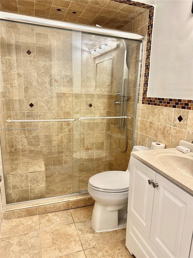 bathroom featuring vanity, a shower with shower door, tile walls, and toilet