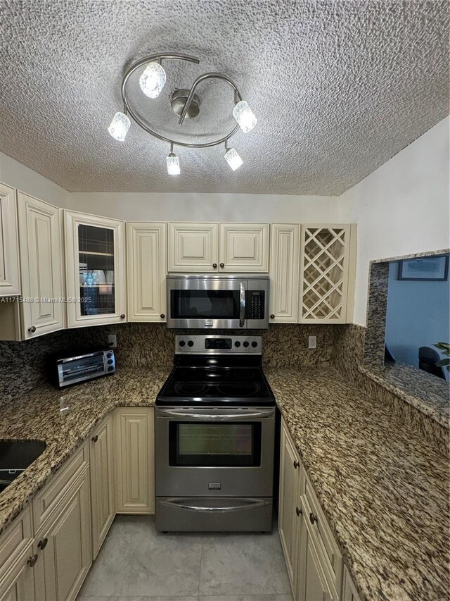 kitchen with backsplash, dark stone countertops, sink, and appliances with stainless steel finishes