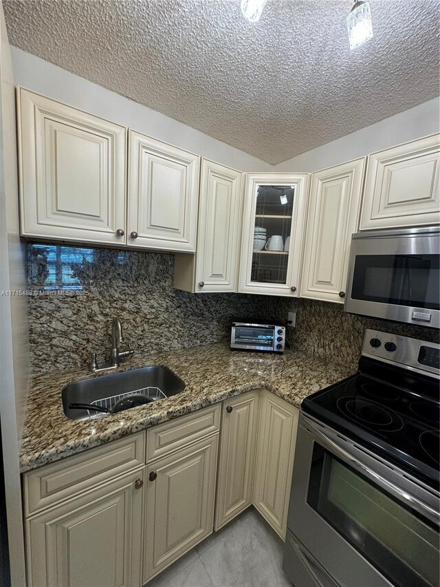 kitchen with stainless steel appliances, kitchen peninsula, a textured ceiling, decorative backsplash, and white cabinets