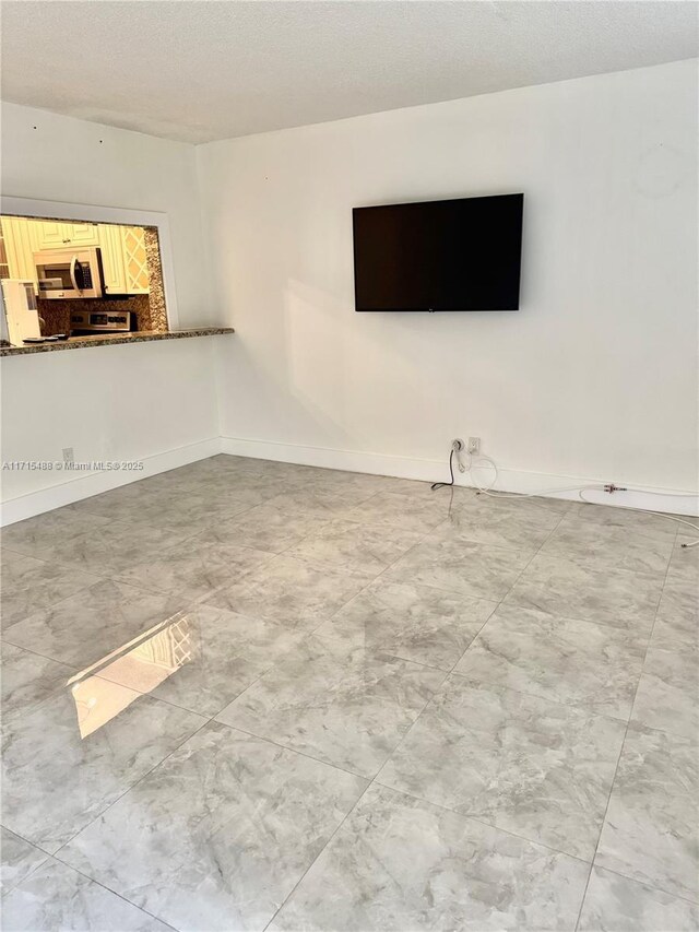 unfurnished living room with ceiling fan and a textured ceiling