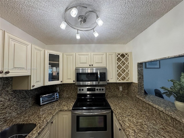 kitchen featuring backsplash, cream cabinets, dark stone counters, and stainless steel appliances