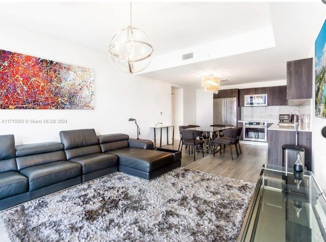 living room featuring a chandelier, light hardwood / wood-style flooring, and sink