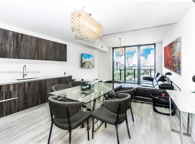 dining area with light hardwood / wood-style flooring, a wall of windows, sink, and an inviting chandelier