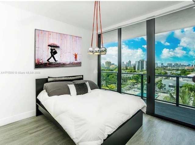 bedroom featuring access to exterior, wood-type flooring, and floor to ceiling windows