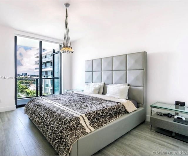 bedroom featuring wood-type flooring and a wall of windows