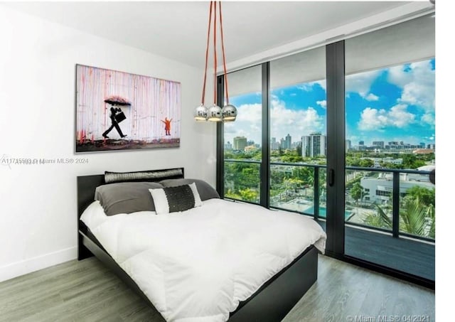 bedroom with access to exterior, hardwood / wood-style floors, and multiple windows