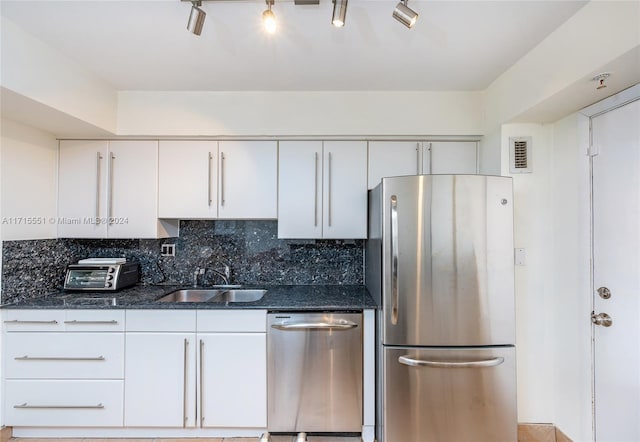 kitchen with backsplash, white cabinets, sink, dark stone countertops, and stainless steel appliances