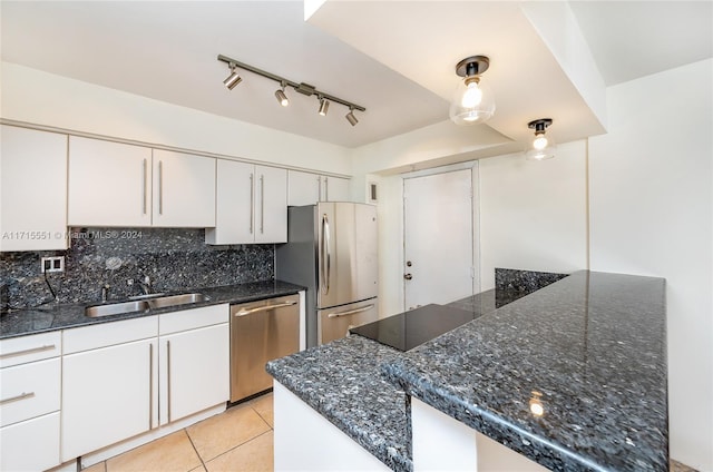 kitchen featuring decorative backsplash, stainless steel appliances, sink, light tile patterned floors, and white cabinetry