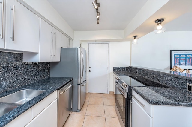 kitchen with rail lighting, light tile patterned floors, tasteful backsplash, stainless steel dishwasher, and white cabinets