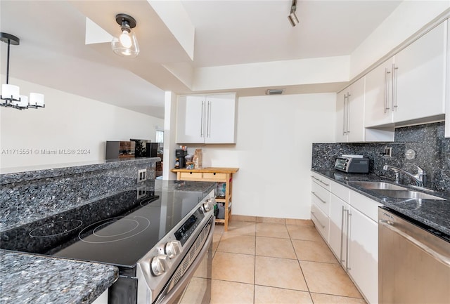 kitchen featuring stainless steel appliances, sink, light tile patterned floors, decorative light fixtures, and white cabinetry