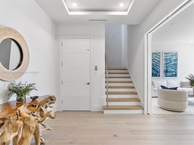 entrance foyer featuring a tray ceiling and light hardwood / wood-style floors