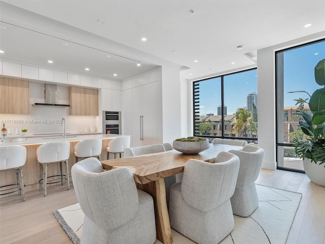 dining room with plenty of natural light, a wall of windows, and light wood-type flooring