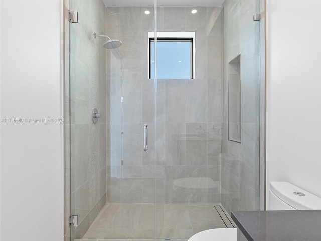 bathroom featuring toilet and a shower with shower door