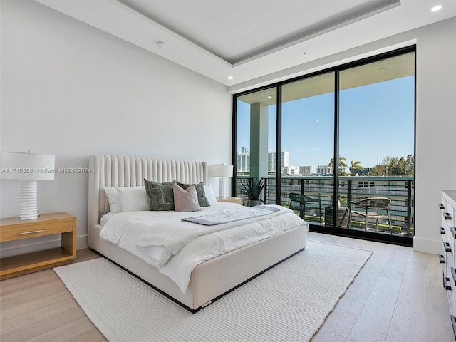 bedroom with access to exterior, expansive windows, multiple windows, and light wood-type flooring