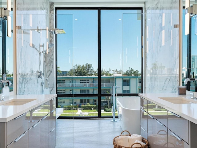 bathroom featuring a bathing tub, expansive windows, sink, and tile patterned floors