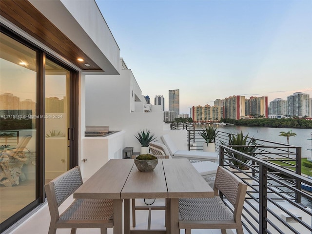 balcony at dusk featuring a water view