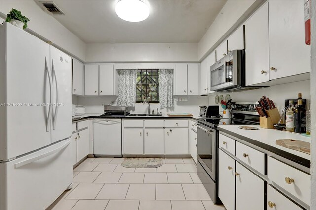 kitchen with light tile patterned flooring, appliances with stainless steel finishes, white cabinetry, and sink